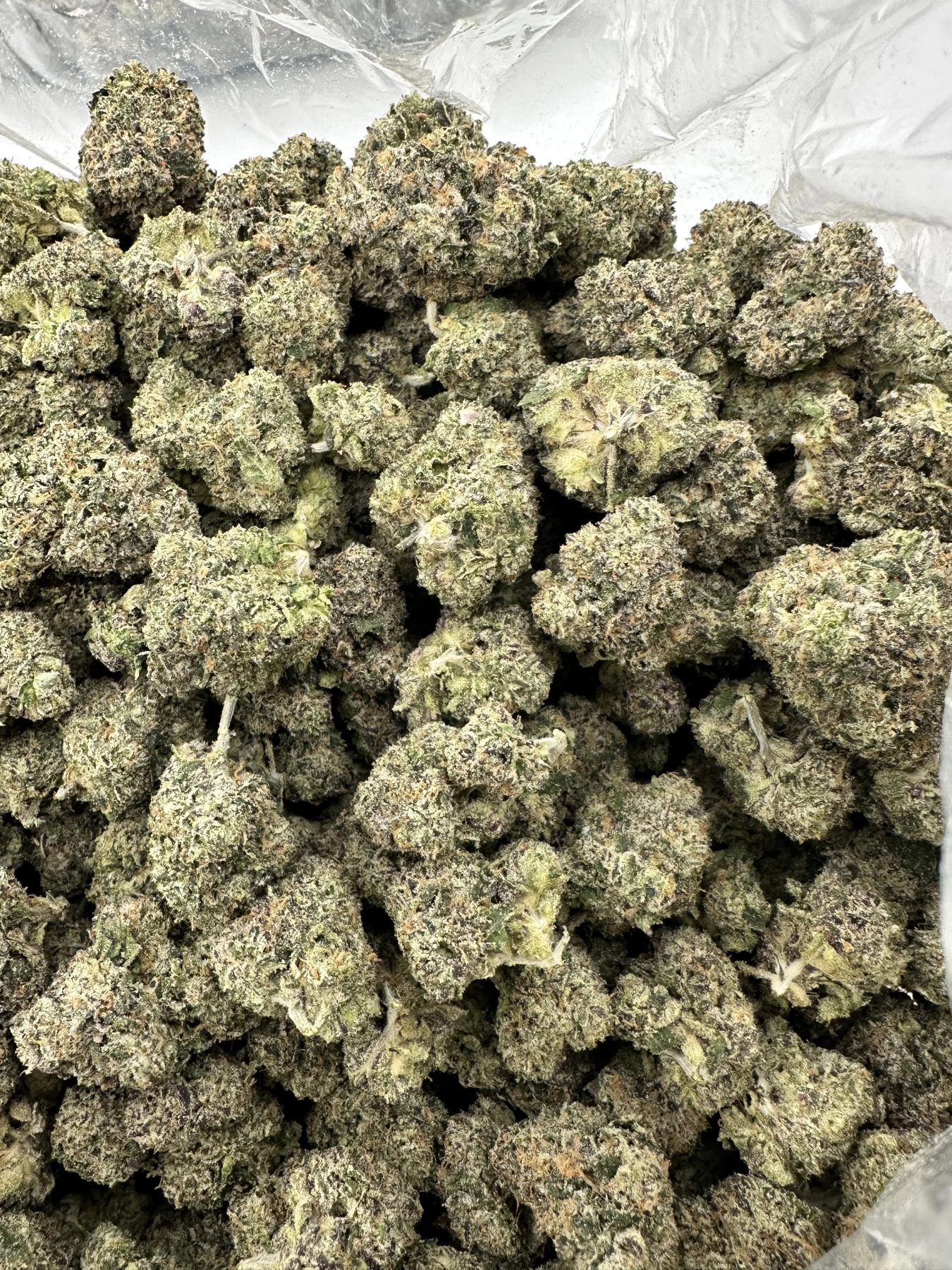 M.O.B. top-shelf flower macro showing hand-selected buds with dense trichome coverage, refined pale green calyx, and curated structure
